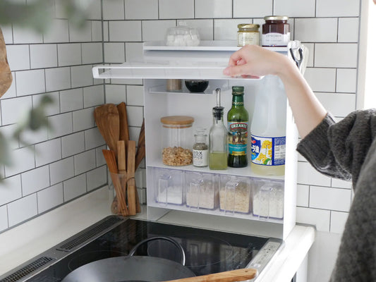 スチール製の前開き調味料ラックがキッチンのカウンタートップに設置され、複数の棚と調味料ボトルが整然と収納されている様子