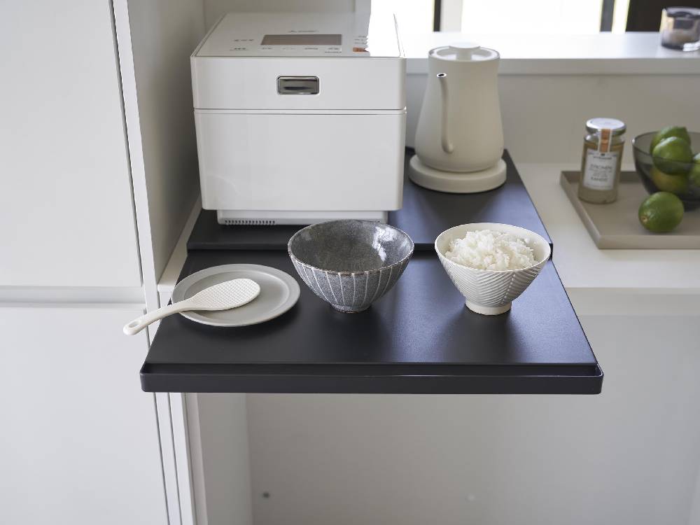 タワーキッチン家電下スライドテーブルに銀製の食器やティーポット、カップなどのキッチン用品が整然と配置された様子