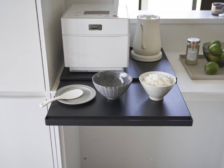 タワーキッチン家電下スライドテーブルに銀製の食器やティーポット、カップなどのキッチン用品が整然と配置された様子