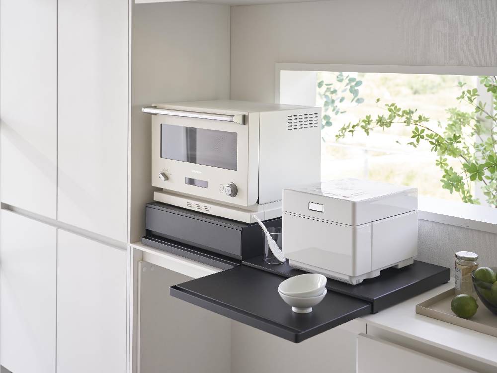 タワーキッチン家電下スライドテーブルの製品画像。スチール製の天板とスライド可能なテーブルがキッチンキャビネットの下に設置されている様子。