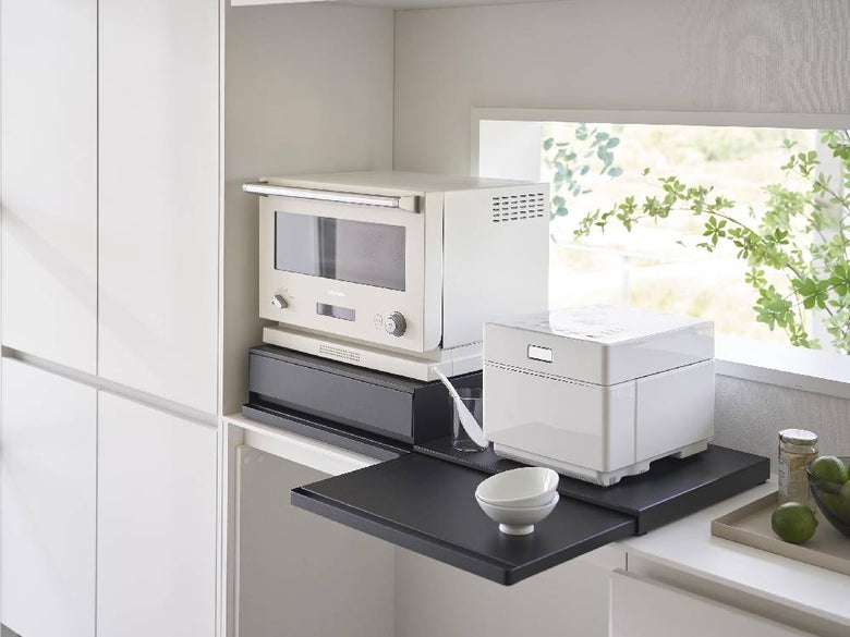 タワーキッチン家電下スライドテーブルの製品画像。スチール製の天板とスライド可能なテーブルがキッチンキャビネットの下に設置されている様子。