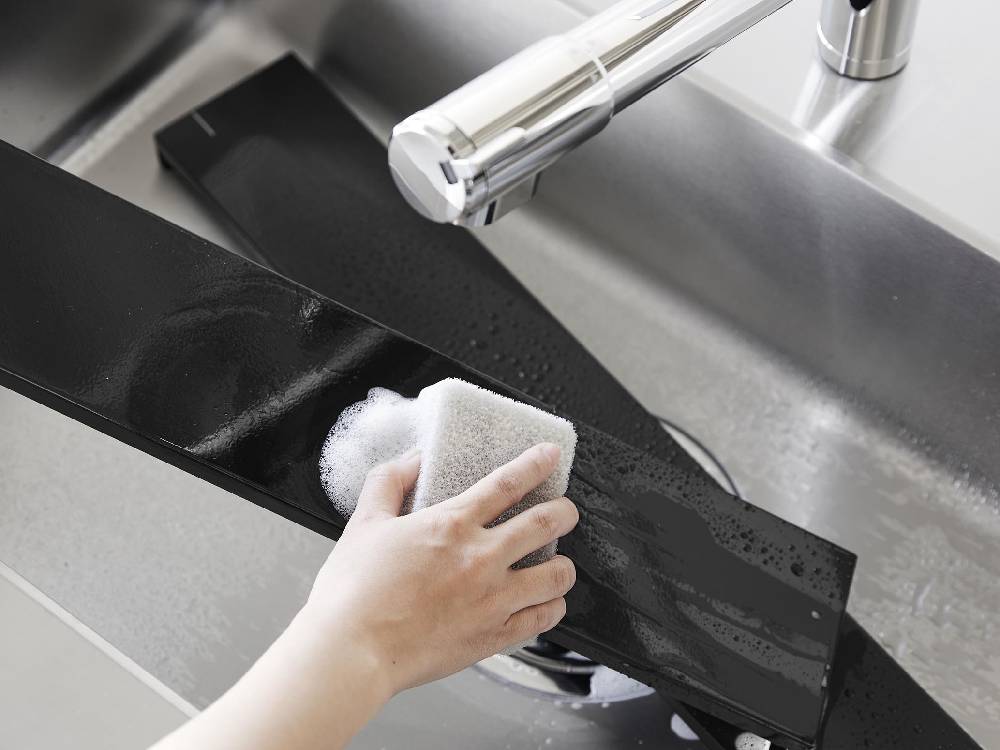 キッチンカウンターに設置された銀色のシンクと蛇口、排気口カバーが配置された台所の様子