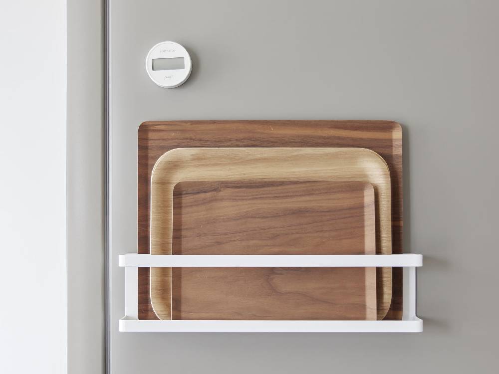 スチール製のマグネット冷蔵庫横サプリ＆調味料ラックが、キッチンの平らなスチール壁面に設置され、フックと棚に調味料やサプリメントが掛けられている様子