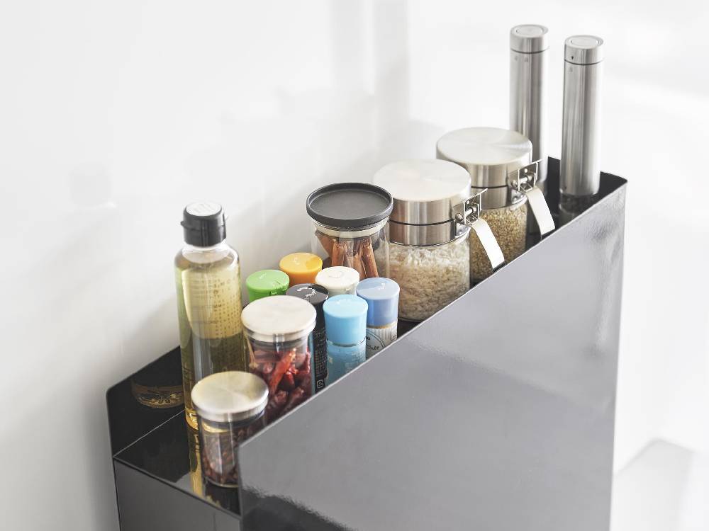 キッチンカウンターに設置されたスチール製2段の隠せる調味料ラックに、ボトルや調理器具が整然と並んでいる様子