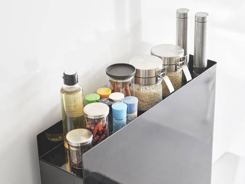 キッチンカウンターに設置されたスチール製2段の隠せる調味料ラックに、ボトルや調理器具が整然と並んでいる様子
