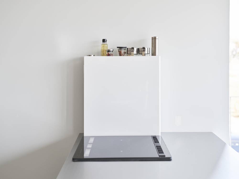 スチール製の2段隠せる調味料ラックがキッチンのカウンタートップに配置され、周囲にシェルフや厨房家電が見える様子