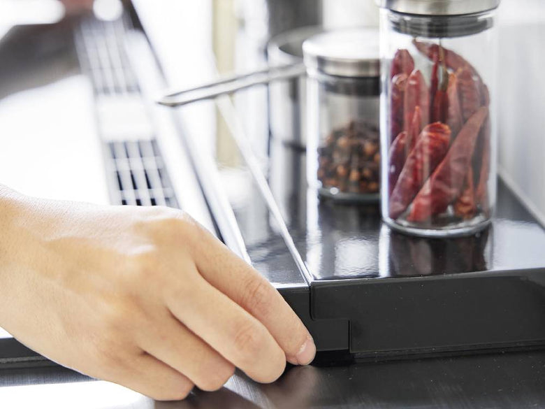 キッチンカウンターに設置された75cmコンロ用伸縮排気口カバーと周囲の家電や食器が並ぶ台所の様子