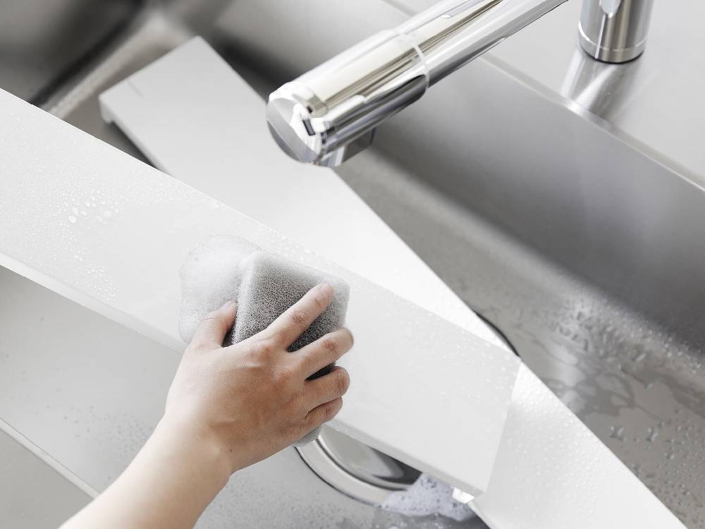 キッチンカウンターに取り付けられたタワー奥行伸縮排気口カバーと銀色のシンクおよび蛇口