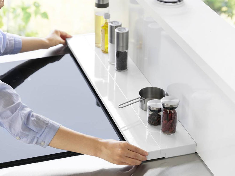 キッチンのカウンタートップに取り付けられたスチール製の奥行伸縮排気口カバーと周囲の家庭用電化製品が配置されたインテリア