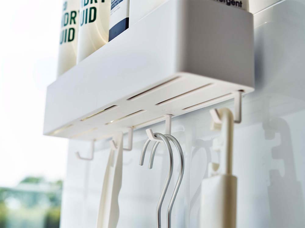 白色のフィルムフックラック W30が壁面に設置され、衣類を掛けるための棚として使用されているインテリアデザイン