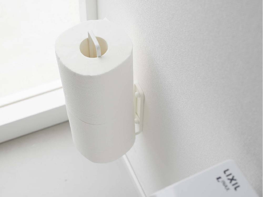 スチール製のタワー型ウォールトイレットペーパーホルダーが壁に取り付けられ、一般的なトイレットロール2本を保持している様子