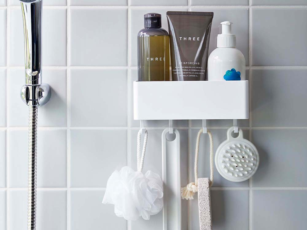 白色のフィルムフックラックが浴室の壁に取り付けられ、ソープディスペンサーやタオル、歯ブラシホルダーなどが整然と配置された清潔なバスルーム
