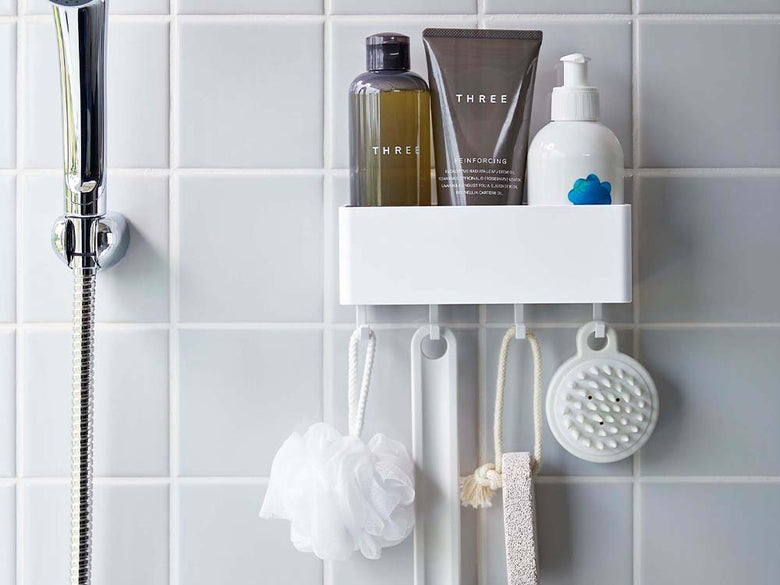 白色のフィルムフックラックが浴室の壁に取り付けられ、ソープディスペンサーやタオル、歯ブラシホルダーなどが整然と配置された清潔なバスルーム