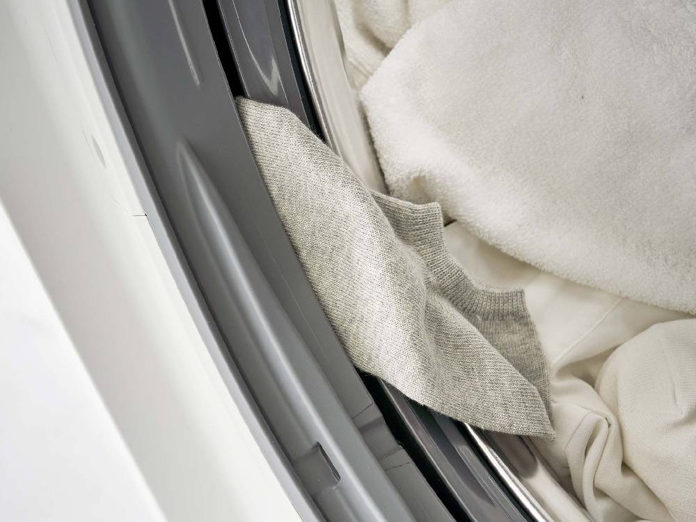 シルバー色のシリコーン製カバーがドラム式洗濯機のドアパッキンに取り付けられている様子