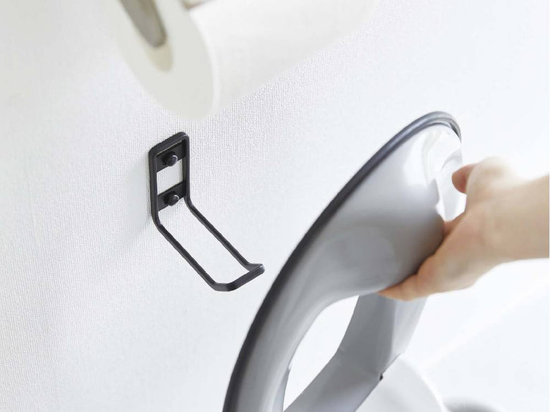 銀色のスチール製ウォールトイレ用品収納フックがバスルームの壁に取り付けられ、トイレットペーパーとペーパータオルが掛けられている様子