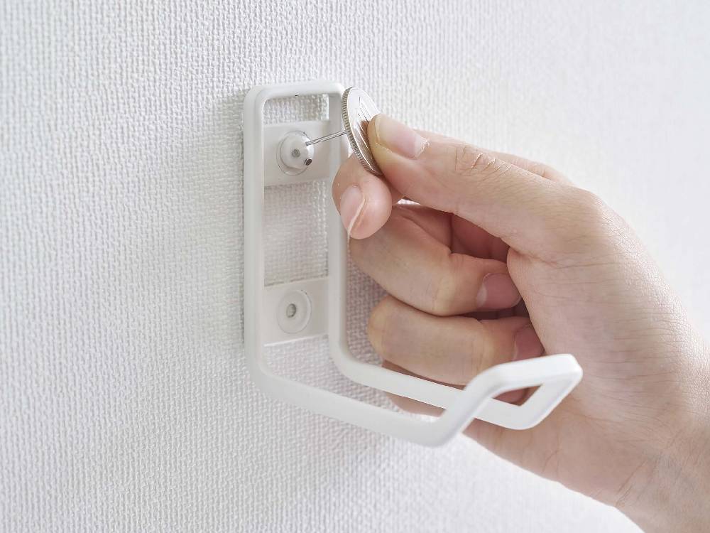 シルバーとプラスチック製のタワー型ウォールトイレ用品収納フックが壁に取り付けられている様子