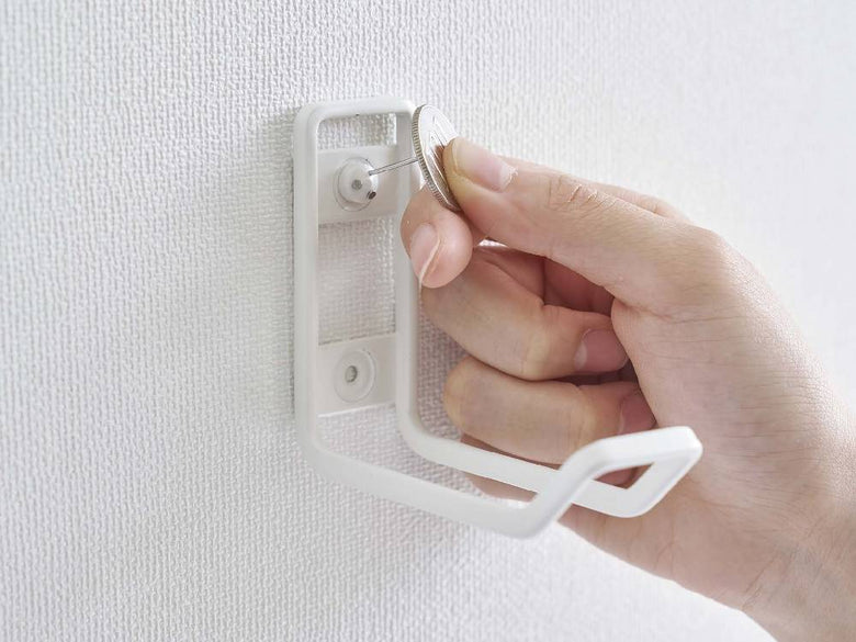 シルバーとプラスチック製のタワー型ウォールトイレ用品収納フックが壁に取り付けられている様子