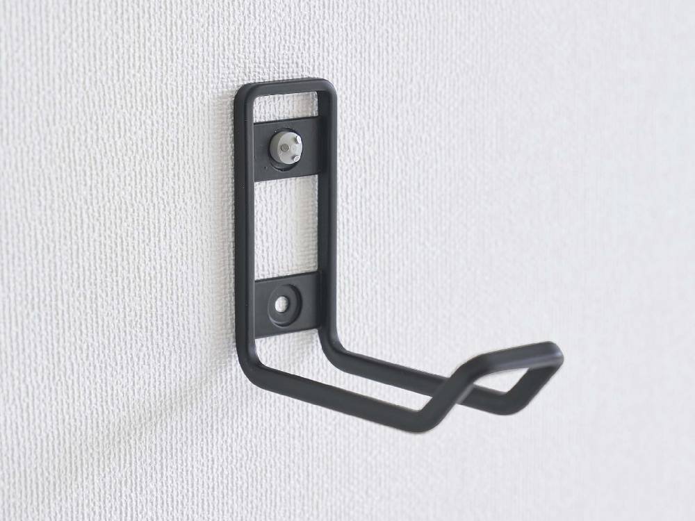 銀色のタワー型ウォールトイレ用品収納フックが壁に取り付けられている様子