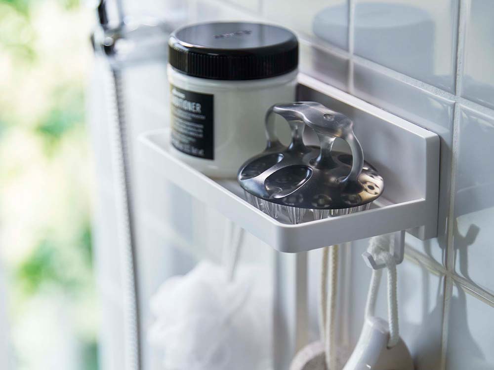 白いABS樹脂製フィルムフックトレーがガラスの棚に設置され、プラスチック製のボトルや家庭用品が整理されているバスルームの様子