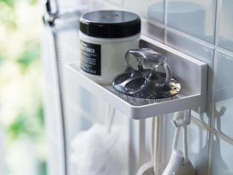 白いABS樹脂製フィルムフックトレーがガラスの棚に設置され、プラスチック製のボトルや家庭用品が整理されているバスルームの様子