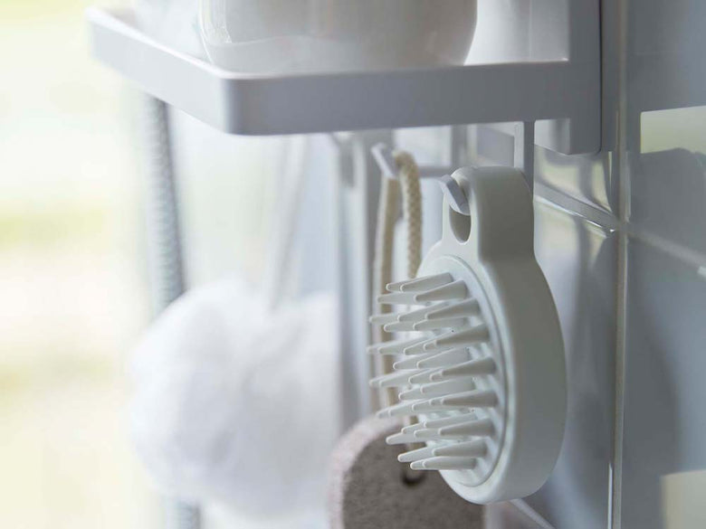 白色のフィルムフックトレーが浴室の壁に設置され、複数のフックでタオルや小物が掛けられている様子