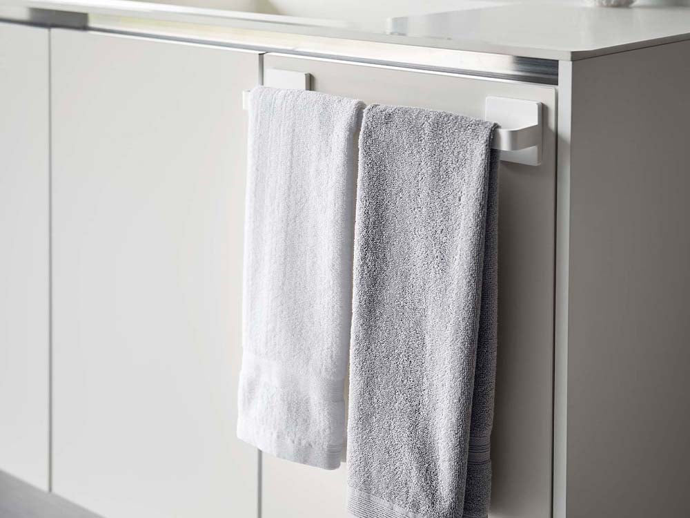 ホワイトのフィルムフック タオルハンガー W36が浴室の壁に取り付けられ、タオルを掛けている様子
