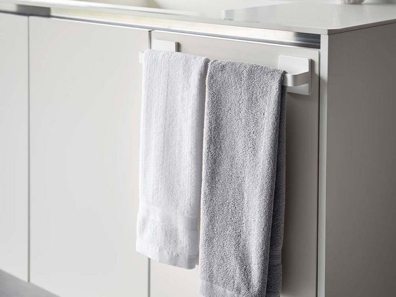 ホワイトのフィルムフック タオルハンガー W36が浴室の壁に取り付けられ、タオルを掛けている様子