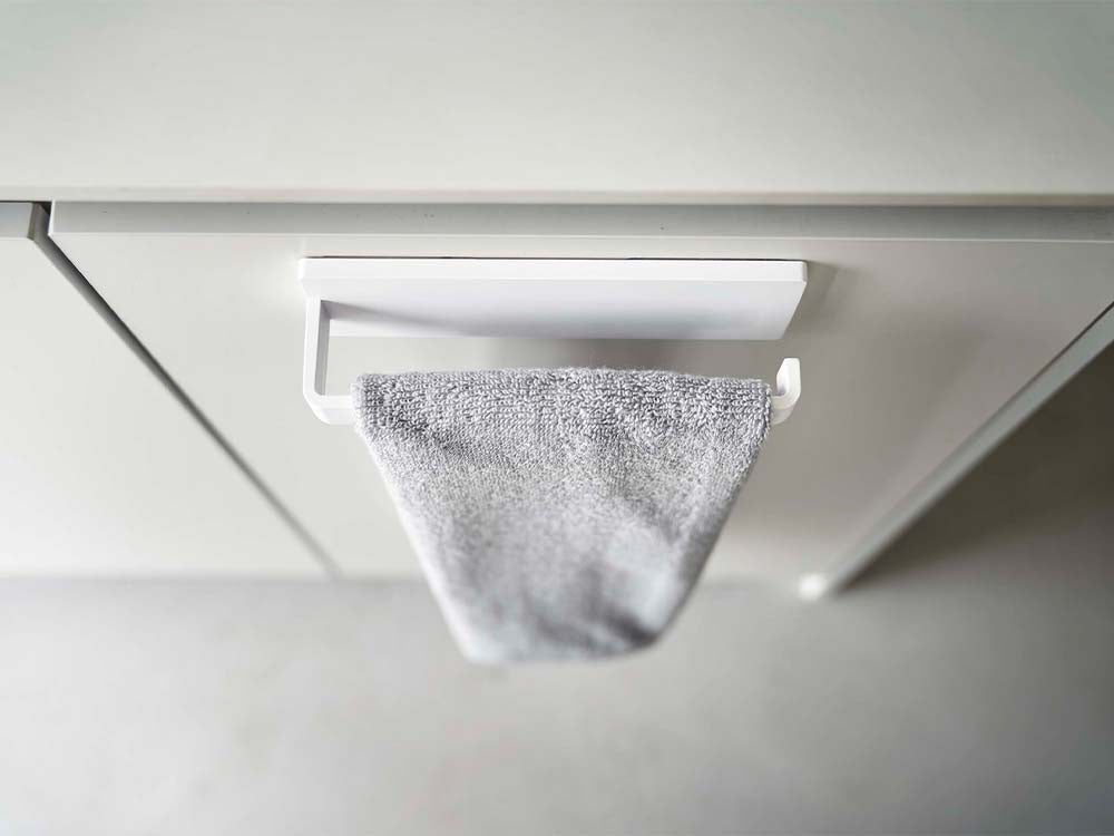 ホワイトカラーのフィルムフックタオルハンガーが壁に装着され、銀色のプラスチック製フックにタオルが掛かっている家庭用収納用品