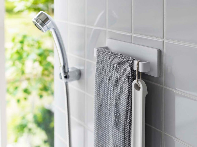 白色のW18フィルムタオルハンガーが光沢のあるバスルームの壁に取り付けられている