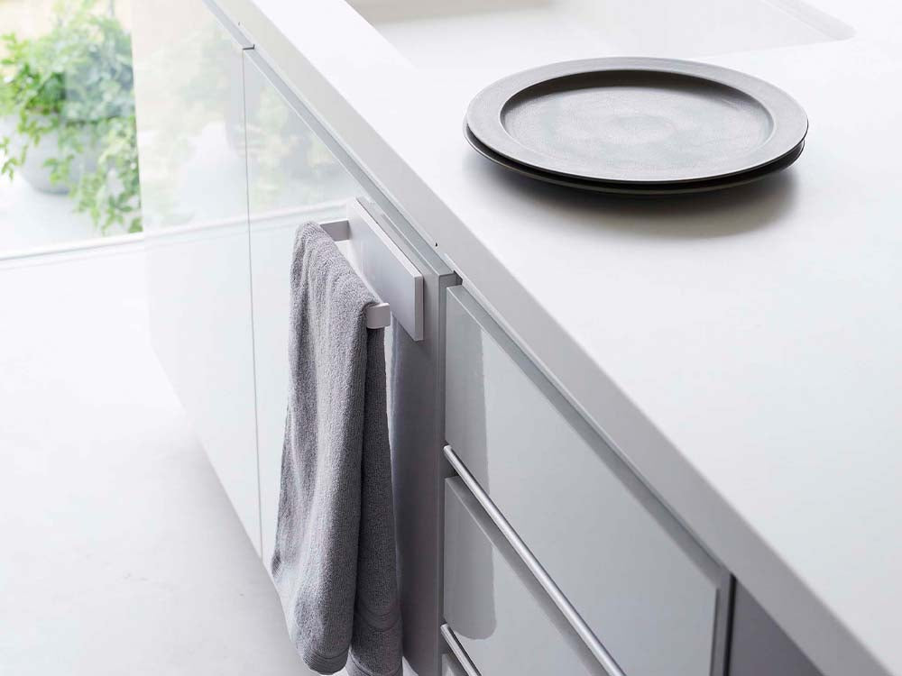 ホワイトのフィルムフックタオルハンガーW18がキッチンカウンターに取り付けられ、シンクや調理器具とともに配置されている様子