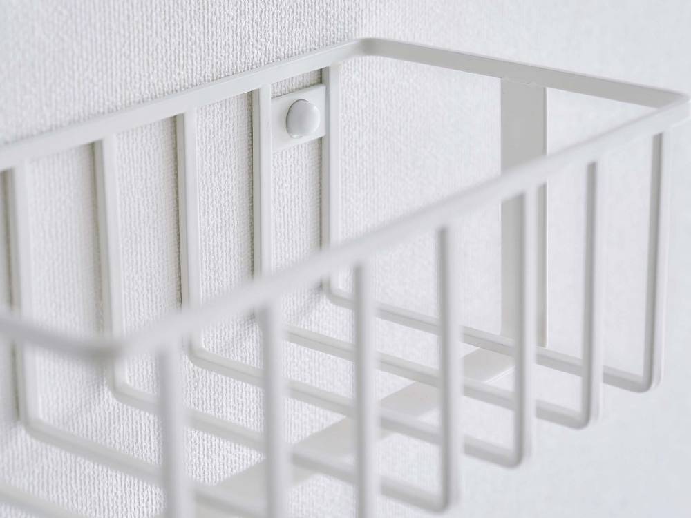 赤ちゃんの安全を考慮したメッシュデザインのウォールトイレ用品収納ラックが、ナースリーのベビーベッド近くに設置されている様子。プラスチック製で使いやすい。