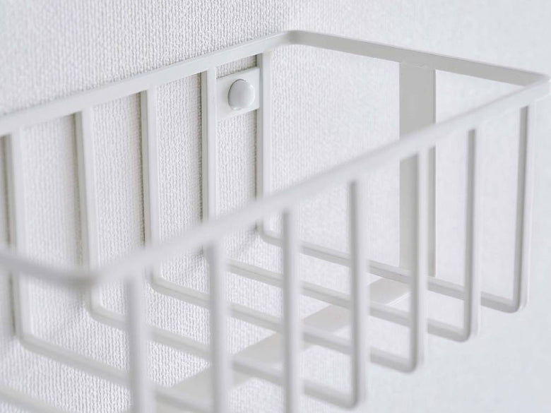 赤ちゃんの安全を考慮したメッシュデザインのウォールトイレ用品収納ラックが、ナースリーのベビーベッド近くに設置されている様子。プラスチック製で使いやすい。