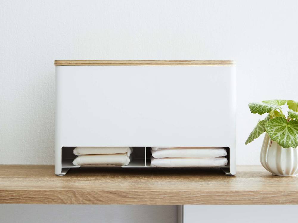 スチールと天然木製の分別サニタリー収納ホルダーが棚に置かれ、花鉢や収納バスケットなどの家庭用品と共に整理整頓されている様子