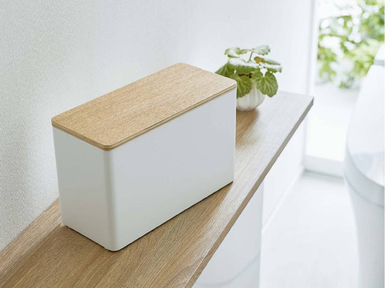 スチールと天然木で作られた【RIN/リン】分別サニタリー収納ホルダーが、ボックス、ラウドスピーカー、観葉植物と共に配置されている様子