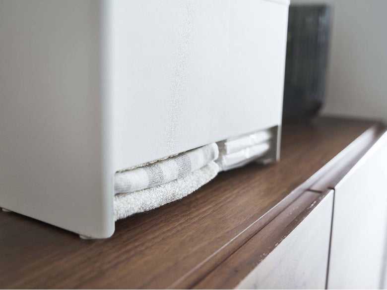 RIN/リンのグレー仕上げ分別サニタリー収納ホルダーが天然木とスチール製の家具上に配置され、シェルフや観葉植物と共にディスプレイされています。