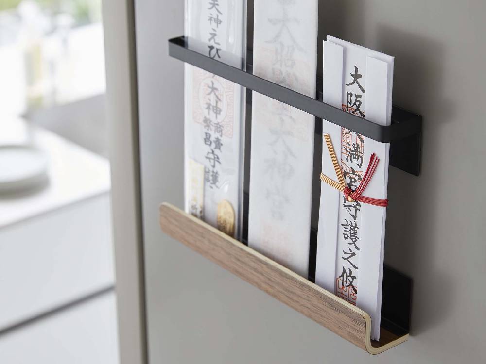 スチールと天然木製の【RIN/リン】マグネット神札ホルダーが棚に置かれ、オフィス用品や文房具と共に整然と配置されている様子