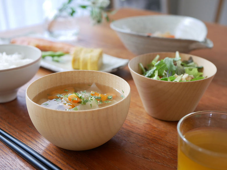 食洗機対応の天然木製マルチボウルに盛られたスープと具材がテーブル上に並べられている様子