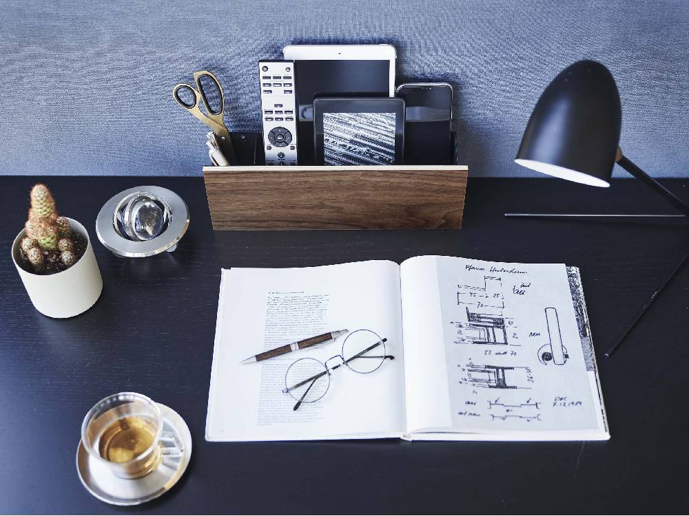 石こうボードに取り付けられたRIN/リン製タブレット＆リモコンホルダー。スチールと木材でできており、充電用ホルダーとフックが付属しています。