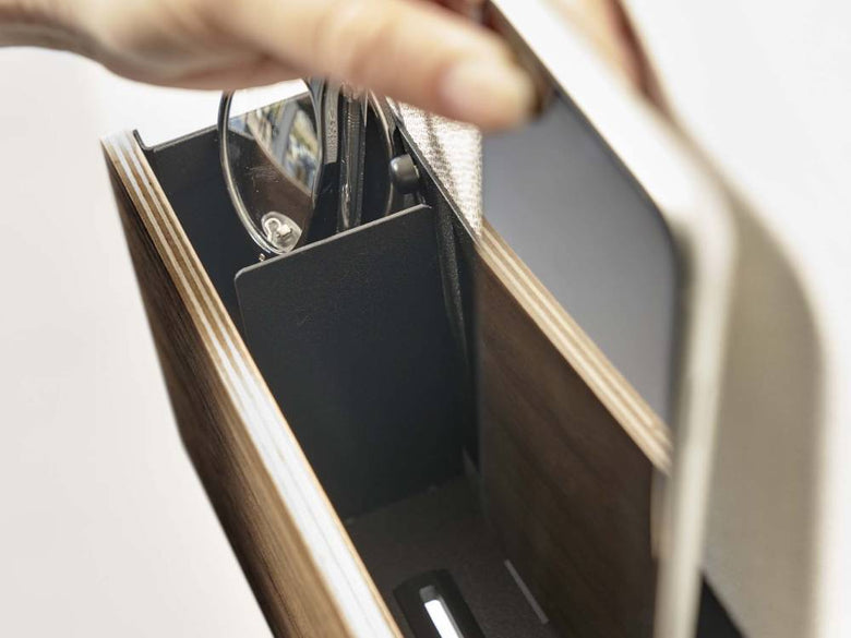 銀色のスチールと木目仕上げの石こうボード対応タブレット＆リモコンホルダーが壁に設置されている様子