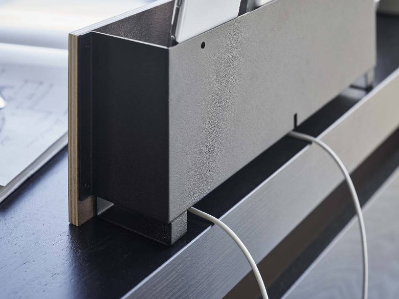 シルバーのスチール製タブレット＆リモコンホルダーが石こうボードの壁に取り付けられている様子