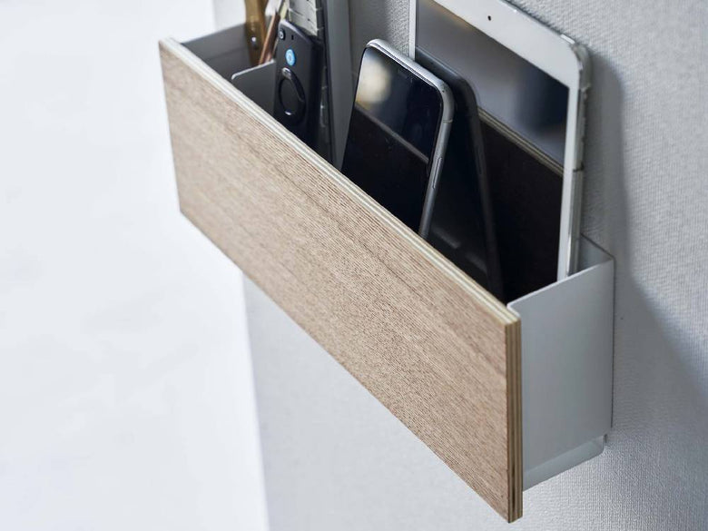 木製と銀色のスチールで作られたタブレットおよびリモコンホルダーが引き出しと棚付きのオフィス用収納キャビネットとして配置されている様子