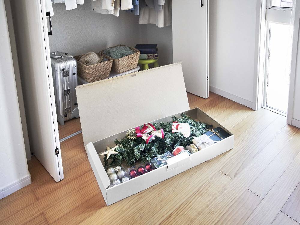 木製の着物収納ボックスが木のフローリングの上に配置され、周囲に観葉植物やキャビネットが並ぶ室内の様子