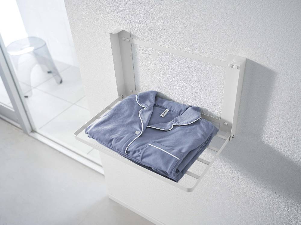 タワー型石こうボード対応折り畳み棚に衣類ハンガーや家庭用品が整理されている様子