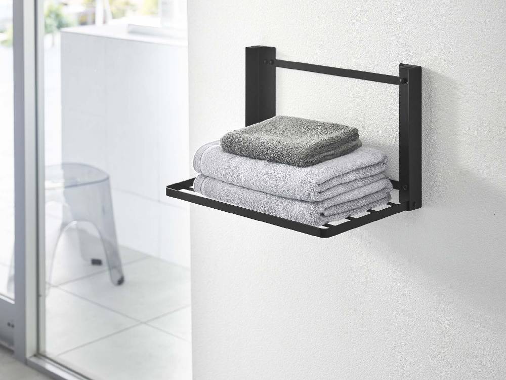 タワー折り畳み棚が浴室の壁に取り付けられ、紙タオルやタオルなどの家庭用品を整理している様子