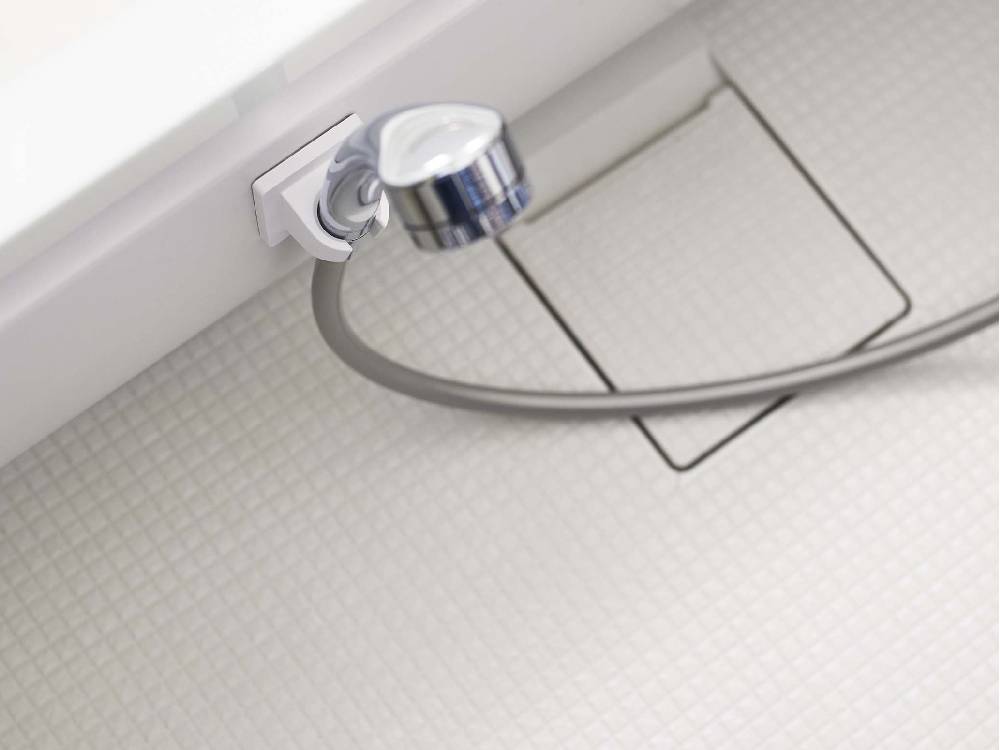 銀色のフィルムフックシャワーホルダーがタイル張りのバスルーム壁に取り付けられている様子