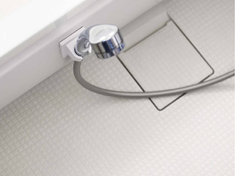 銀色のフィルムフックシャワーホルダーがタイル張りのバスルーム壁に取り付けられている様子