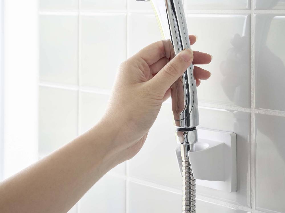 浴室の壁に取り付けられた「MIST/ミスト」フィルムフックシャワーホルダー。銀色のABS樹脂製ホルダーにポリカーボネート製のフィルムフックが付いている