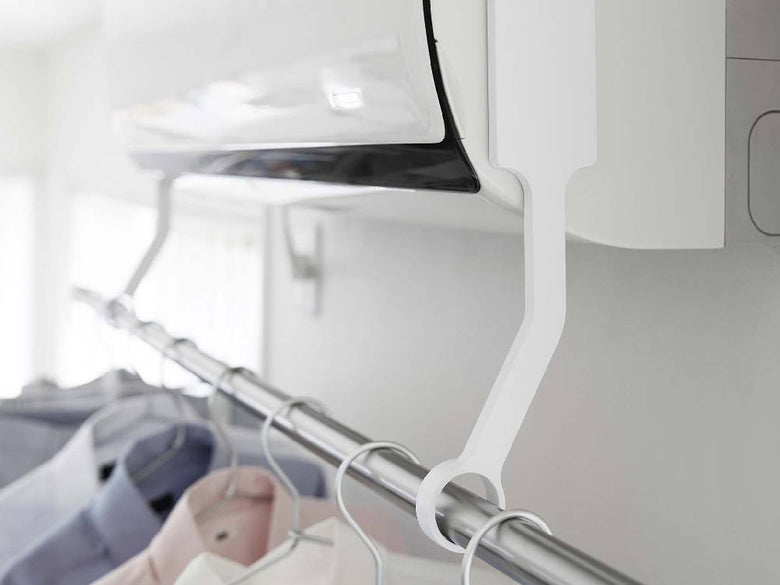 アルミ製の【tower/タワー】フィルムフックエアコン室内物干しポールホルダーがエアコンに取り付けられ、棚や電気ケーブルが整理されたデザイン