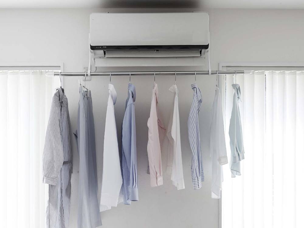 フィルムフックエアコン室内物干しポールホルダーに掛けられた衣類とカーテンが配置された室内の様子