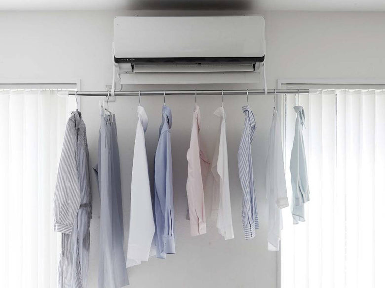 フィルムフックエアコン室内物干しポールホルダーに掛けられた衣類とカーテンが配置された室内の様子